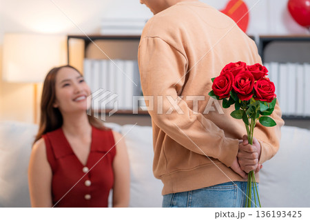 Romantic asian man hiding rose bouquet to surprise girlfriend with celebrating Valentine's Day. 136193425