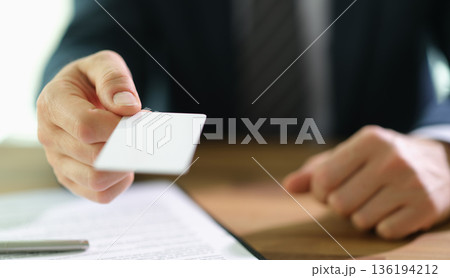Professional exchanging a business card during an important meeting in a modern office setting 136194212