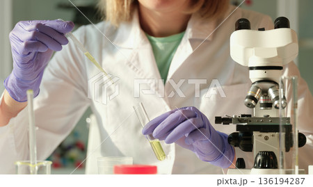 Scientist conducting a fascinating experiment in a bright laboratory filled with colorful samples and advanced equipment 136194287