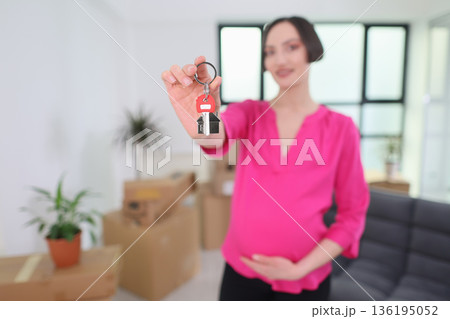 New beginnings unfold as a pregnant woman holds keys in her bright living room filled with boxes New beginnings unfold as a pregnant woman holds keys in her bright living room filled with boxes 136195052