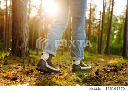 Hiker's boots stepping on a blanket of fallen autumnal orange leaves in the forest. Travel 136195570