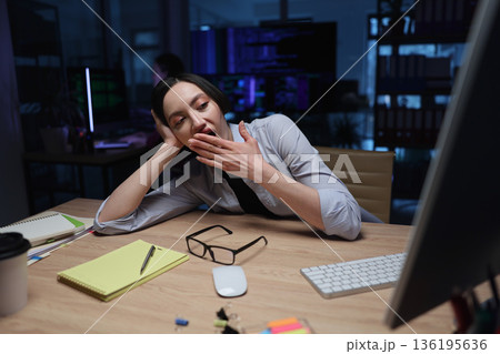 Late night work creates a sleepy atmosphere for a focused professional in a modern office space Late night work creates a sleepy atmosphere for a focused professional in a modern office space 136195636