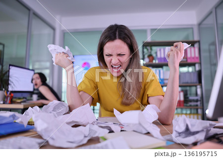 Frustrated office worker battles paperwork chaos in a bustling workspace during a busy afternoon Frustrated office worker battles paperwork chaos in a bustling workspace during a busy afternoon 136195715