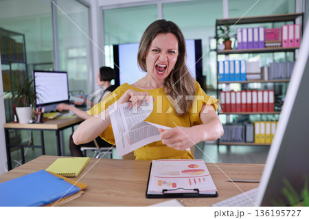 Frustration unveiled in the modern office as a woman tears reports during a stressful workday Frustration unveiled in the modern office as a woman tears reports during a stressful workday 136195727