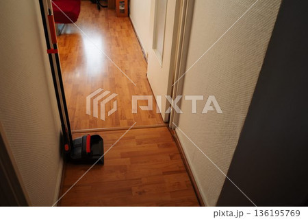 Tall broom and dust pan standing in an apartment corridor. Simple everyday home interior scene showing basic cleaning tools stored indoors for routine household maintenance. Tall broom and dust pan standing in an apartment corridor. Simple everyday home interior scene showing basic cleaning tools stored indoors for routine household maintenance. 136195769