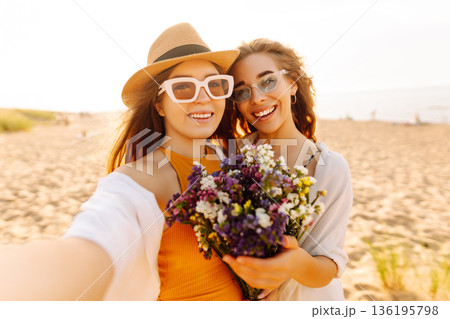 Two pretty friends women making selfie on beach, light and bright summer colors. Friends together Two pretty friends women making selfie on beach, light and bright summer colors. Friends together 136195798