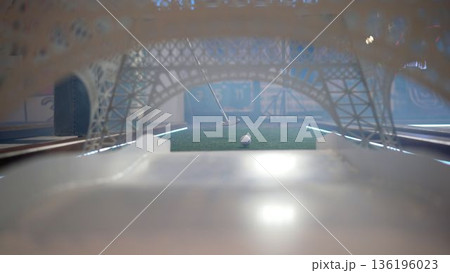 Miniature golf ball rolling through eiffel tower replica into hole Miniature golf ball rolling through eiffel tower replica into hole 136196023