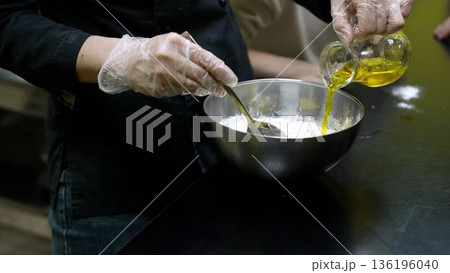 Chef adding olive oil to flour mixture 136196040