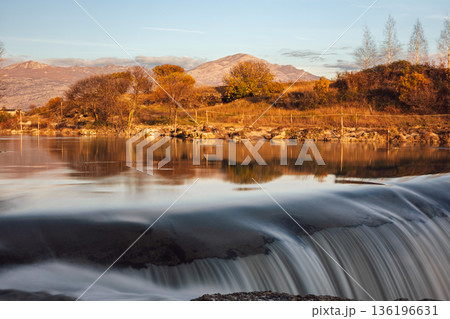 Autumn River Landscape With Waterfall and Mountain Backdrop at Sunset 136196631