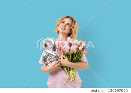 Woman holds flowers and a balloon while celebrating March 8 136197069