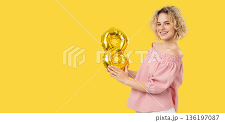 Woman smiles and holds a golden number balloon in celebration Woman smiles and holds a golden number balloon in celebration 136197087