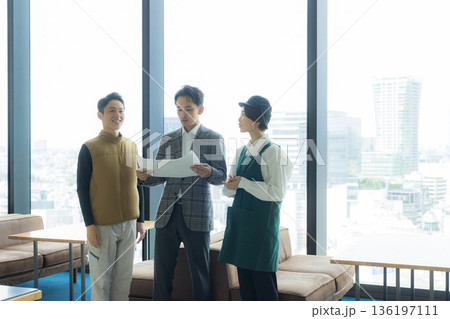 資料を見ながら打ち合わせする空調服の職人の男性 136197111