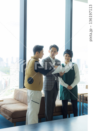 資料を見ながら打ち合わせする空調服の職人の男性 136197113