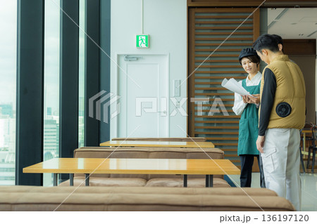 資料を見ながら打ち合わせする空調服の職人の男性 136197120