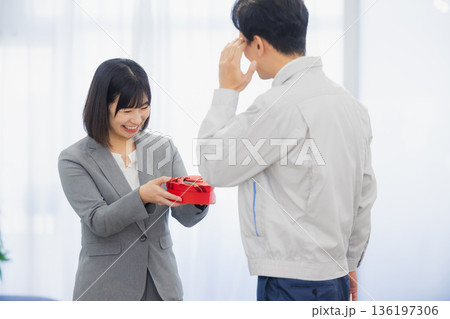 社内で男性にプレゼントを渡す女性 社内で男性にプレゼントを渡す女性 136197306