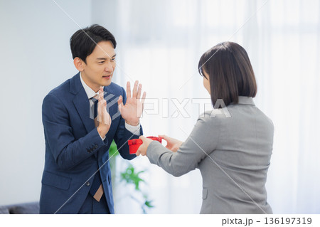 社内で男性にプレゼントを渡す女性 社内で男性にプレゼントを渡す女性 136197319