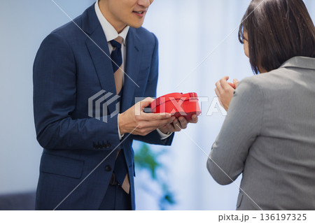 社内で男性にプレゼントを渡す女性 136197325
