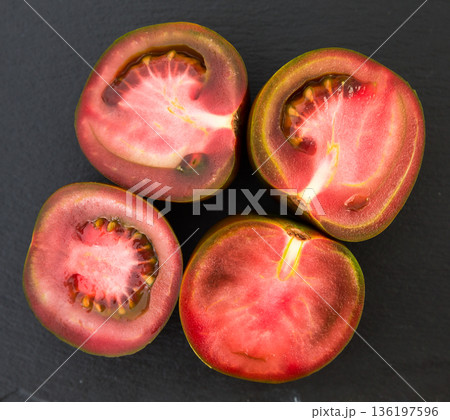 black halves of tomatoes on black stone board black halves of tomatoes on black stone board 136197596