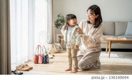 お出かけの準備をして笑顔で娘の上着を整える日本人母親 136199094