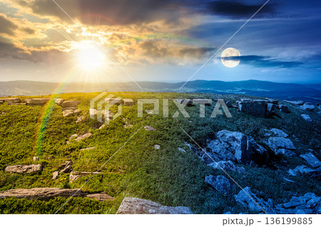 grassy alpine meadow in carpathian mountain landscape on summer solstice. day and night time change concept. sharp rocks and huge boulders among grass on rolling hills with sun and moon at twilight grassy alpine meadow in carpathian mountain landscape on summer solstice. day and night time change concept. sharp rocks and huge boulders among grass on rolling hills with sun and moon at twilight 136199885