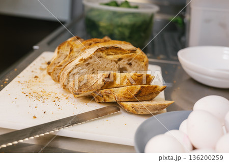 Slicing fresh artisan sourdough bread with eggs 136200259