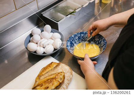 Chef whisking eggs in blue bowl on stainless steel counter Chef whisking eggs in blue bowl on stainless steel counter 136200261