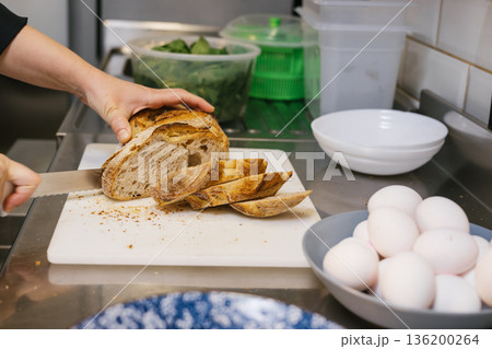 Chef hands slicing sourdough bread on cutting board Chef hands slicing sourdough bread on cutting board 136200264