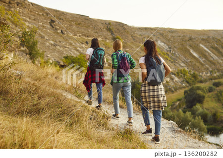 Group of young girls tourists with backpacks hiking in nature walking in a row. Group of young girls tourists with backpacks hiking in nature walking in a row. 136200282