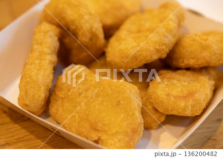 Crispy golden fried chicken nuggets in a white paper container, representing a classic quick service restaurant appetizer, convenient snack, or satisfying takeaway meal 136200482
