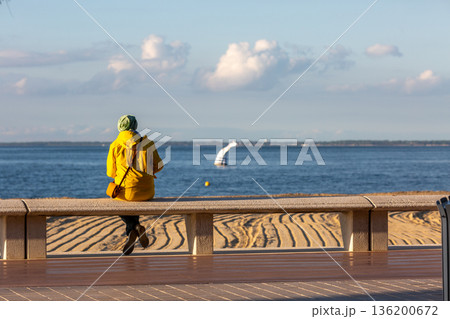 people sitting on a bench looking at the sea 136200672