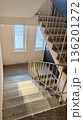 Residential apartment building stairwell with concrete stairs, metal railings and windows, empty interior with natural daylight. 136201272
