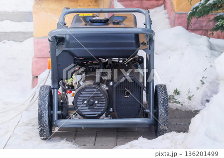 Power supply generator placed on street sidewalk. Mobile diesel generator is running outside in winter. Energy independence and electrical equipment. 136201499