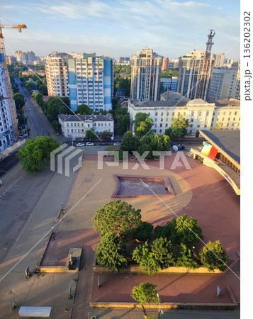 A residential complex in city on a summer morning. Many high-rise multi-story buildings, large fundamental building, a green road on a city street on sunny morning. A residential complex in city on a summer morning. Many high-rise multi-story buildings, large fundamental building, a green road on a city street on sunny morning. 136202302