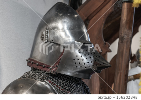 A gleaming medieval knight helmet sits beside chainmail A gleaming medieval knight helmet sits beside chainmail 136202848