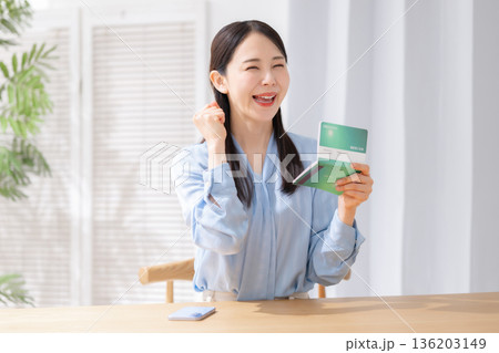 通帳を持ってガッツポーズする女性 通帳を持ってガッツポーズする女性 136203149