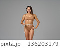 Full-length portrait of fit woman measuring waist with tape showing confidence and body positivity 136203179