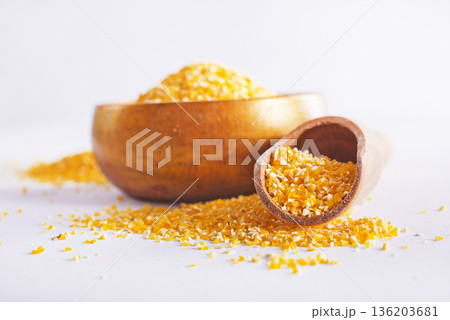 Raw cornmeal flour used in polenta, in wooden bowl 136203681