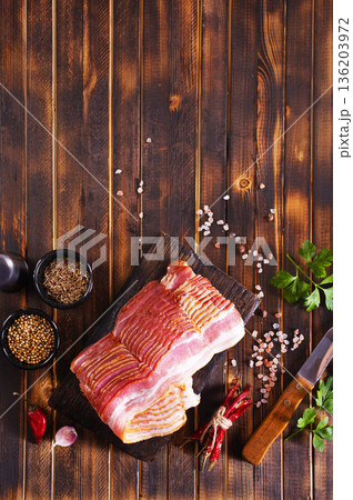 Fresh raw bacon sliced with spices and herbs on a dark concrete background 136203972