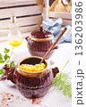 Corn porridge in a clay plate, a clay pot with porridge on a light background 136203986