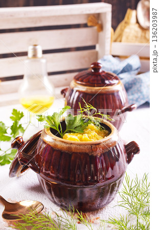 Corn porridge in a clay plate, a clay pot with porridge on a light background Corn porridge in a clay plate, a clay pot with porridge on a light background 136203987
