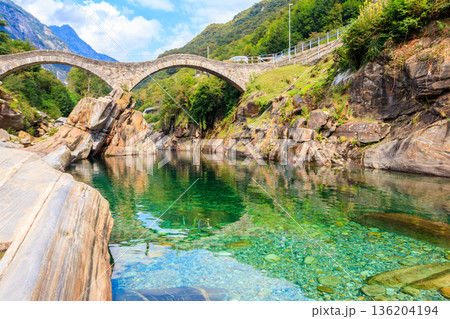Ancient double arch stone Roman bridge (Ponte dei Salti) over the clear water of the Verzasca river in Lavertezzo ,Verzasca Valley, Ticino Canton, Switzerland Ancient double arch stone Roman bridge (Ponte dei Salti) over the clear water of the Verzasca river in Lavertezzo ,Verzasca Valley, Ticino Canton, Switzerland 136204194
