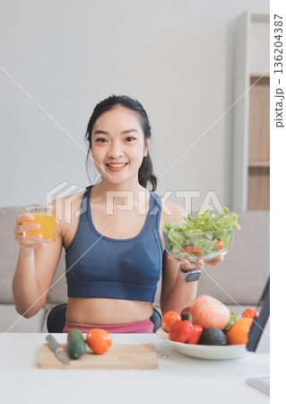 Fit young Asian women in activewear sitting on yoga mat and eating fresh vegetable salad after workout, representing clean eating, fitness lifestyle, wellness routine and health balance. Fit young Asian women in activewear sitting on yoga mat and eating fresh vegetable salad after workout, representing clean eating, fitness lifestyle, wellness routine and health balance. 136204387
