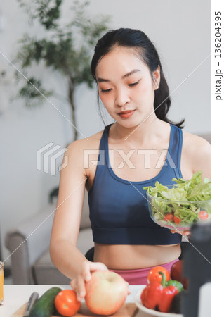 Fit young Asian women in activewear sitting on yoga mat and eating fresh vegetable salad after workout, representing clean eating, fitness lifestyle, wellness routine and health balance. Fit young Asian women in activewear sitting on yoga mat and eating fresh vegetable salad after workout, representing clean eating, fitness lifestyle, wellness routine and health balance. 136204395