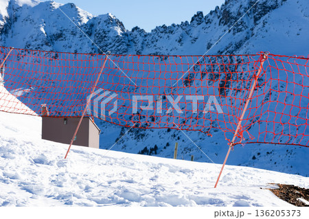 Snowy mountain landscape with red safety net in alpine setting Snowy mountain landscape with red safety net in alpine setting 136205373