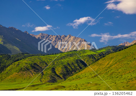Majestic mountain range with green hills and clear blue sky in rural Kyrgyzstan Majestic mountain range with green hills and clear blue sky in rural Kyrgyzstan 136205462