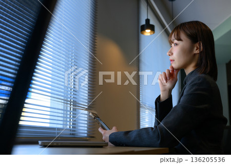 窓際でスマホを見つめる女性 136205536