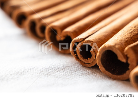 Cinnamon cassia sticks stacked together, showcasing their rich brown color and curled ends. Ideal for culinary and aromatic uses. Cinnamon cassia sticks stacked together, showcasing their rich brown color and curled ends. Ideal for culinary and aromatic uses. 136205785