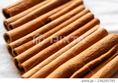 Cinnamon cassia sticks stacked together, showcasing their rich brown color and curled ends. Ideal for culinary and aromatic uses. 136205793