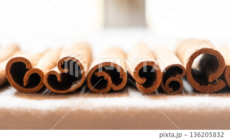 Cinnamon cassia sticks stacked together, showcasing their rich brown color and curled ends. Ideal for culinary and aromatic uses. 136205832