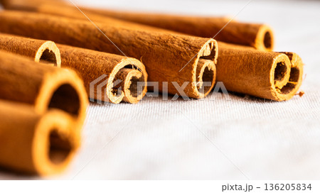 Cinnamon cassia sticks stacked together, showcasing their rich brown color and curled ends. Ideal for culinary and aromatic uses. 136205834